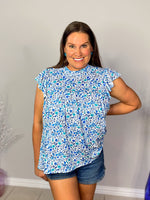 tiered ruffle sleeve top in blue and teal small on white base floral front view hand on hip