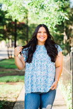 tiered ruffle sleeve top in blue and teal small on white base floral front view plus size hand holding hair